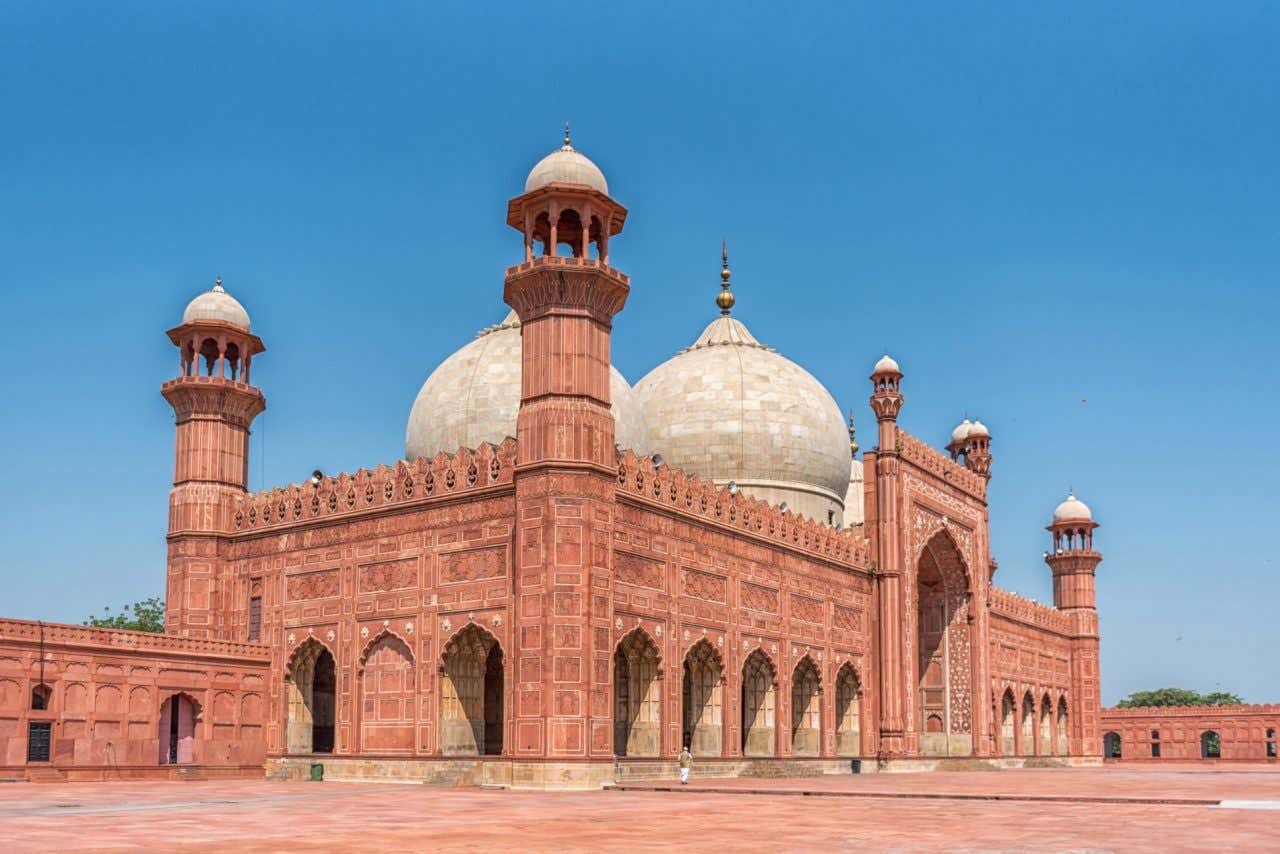 Tonalidade avermelhada da Mesquita de Badshahi com cúpulas brancas