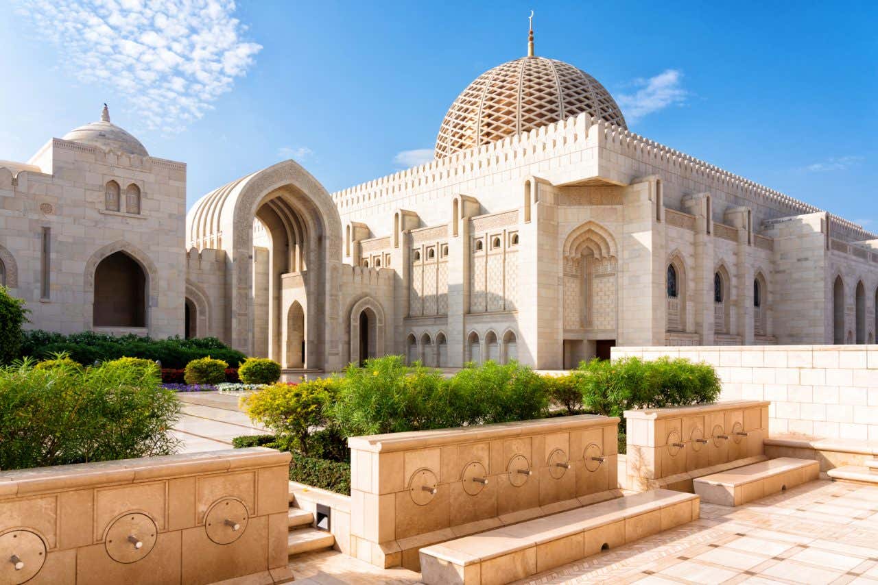 Cor branca domina a fachada da Grande Mesquita do Sultão Qaboos, que conta com detalhes dourados na cúpula