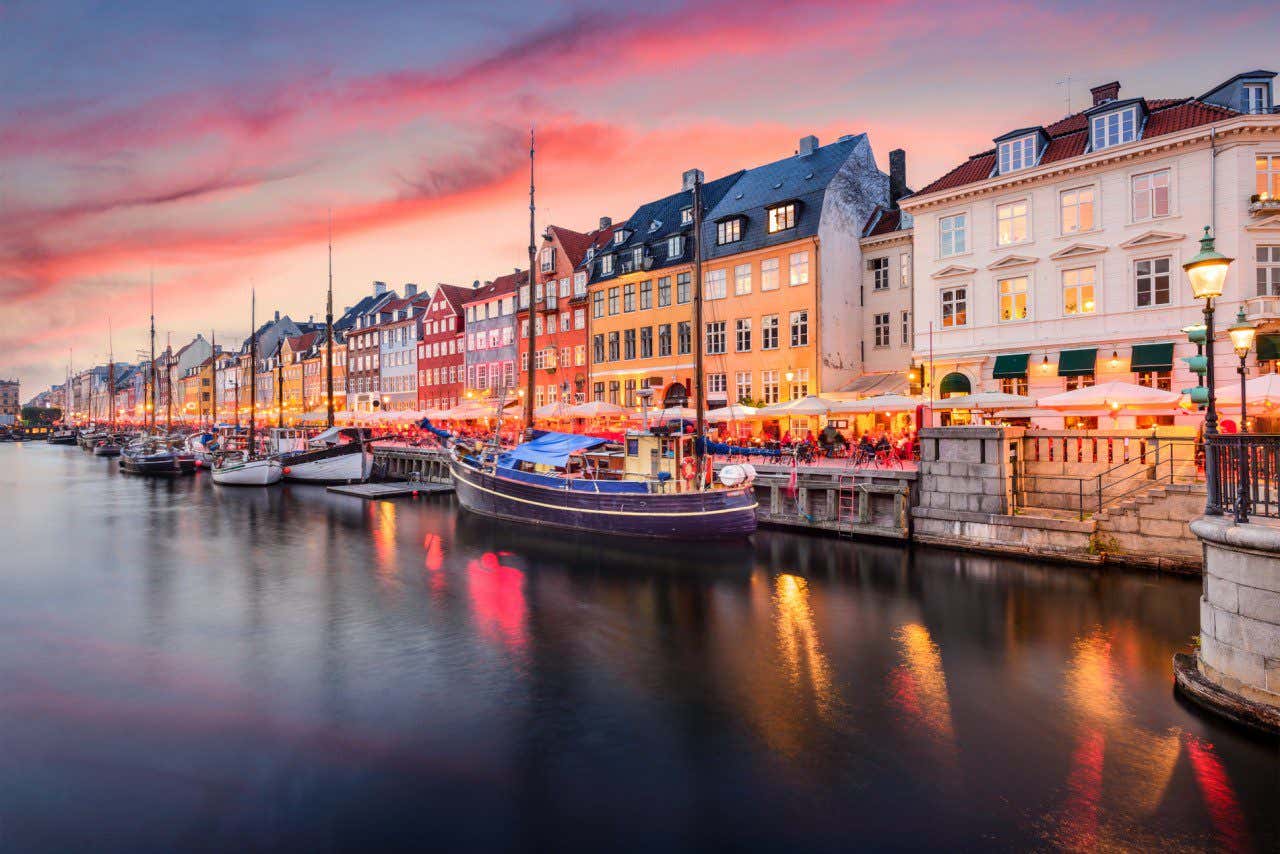 Canal Nyhavn avec des bâtiments illuminés au coucher du soleil à Copenhague