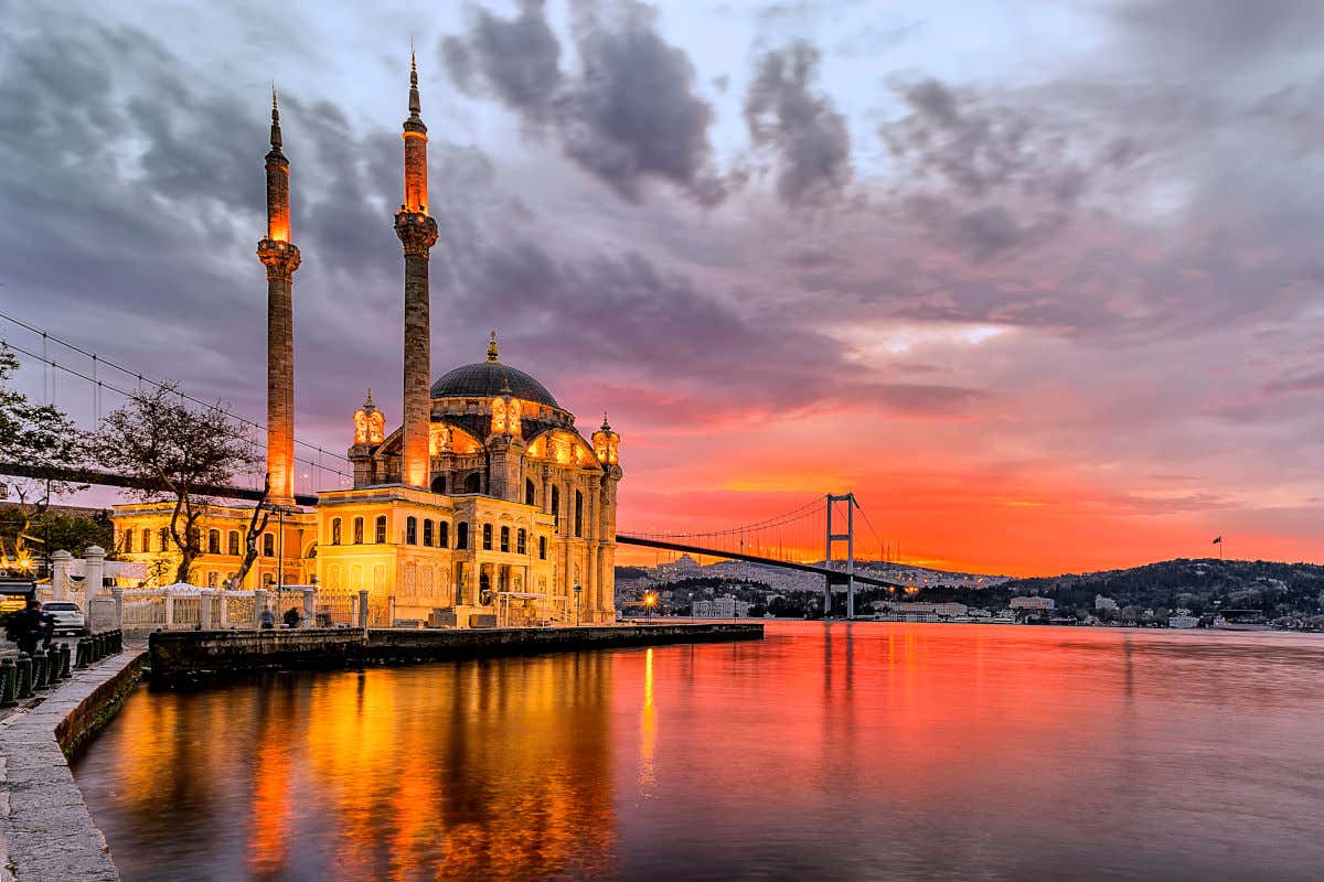 Panorâmica da mesquita de Ortaköy junto ao Bósforo e diante de um belo amanhecer de tons avermelhados em Istambul