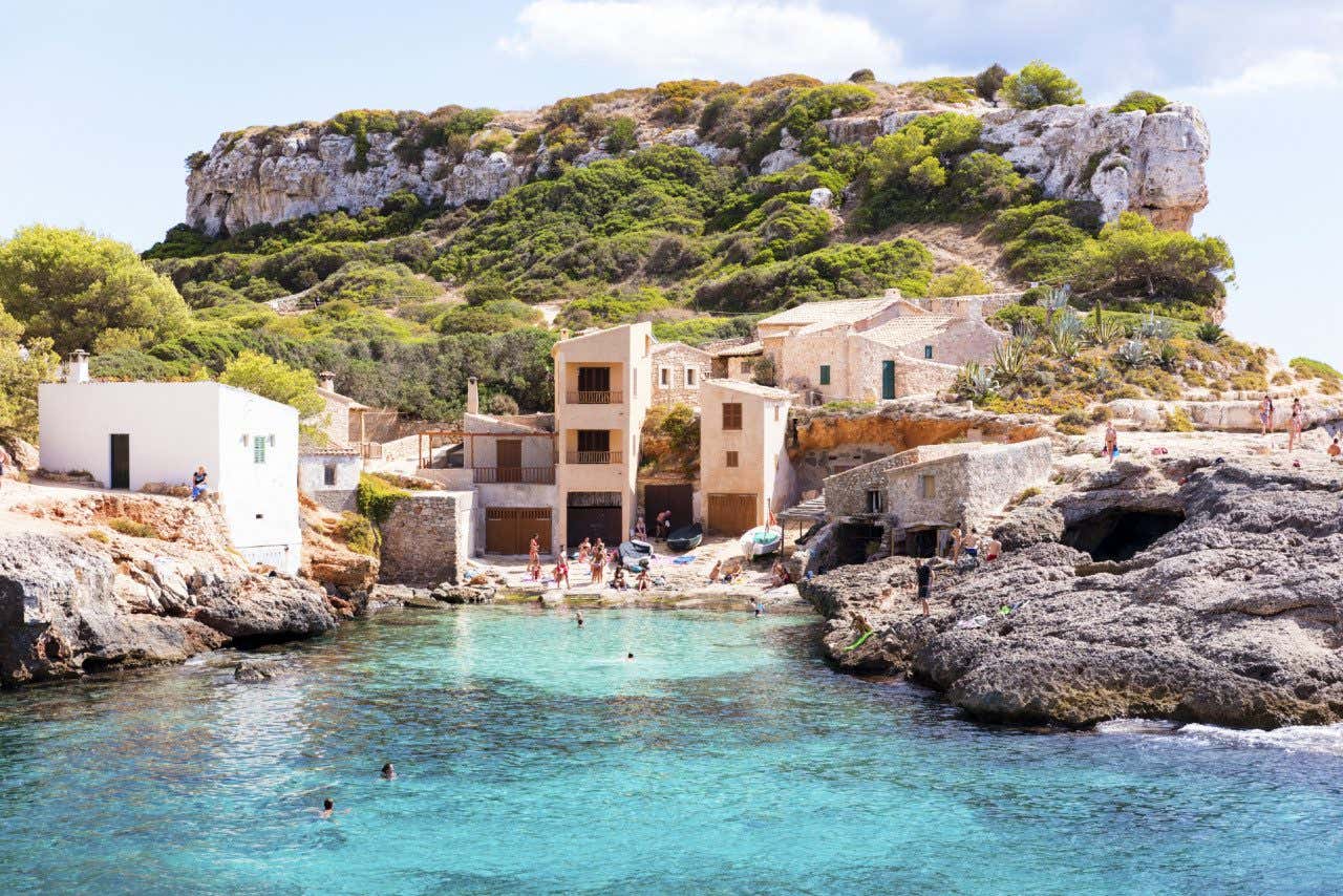 Casas de pescadores entre as rochas em Cala S'Almunia em um dia ensolarado