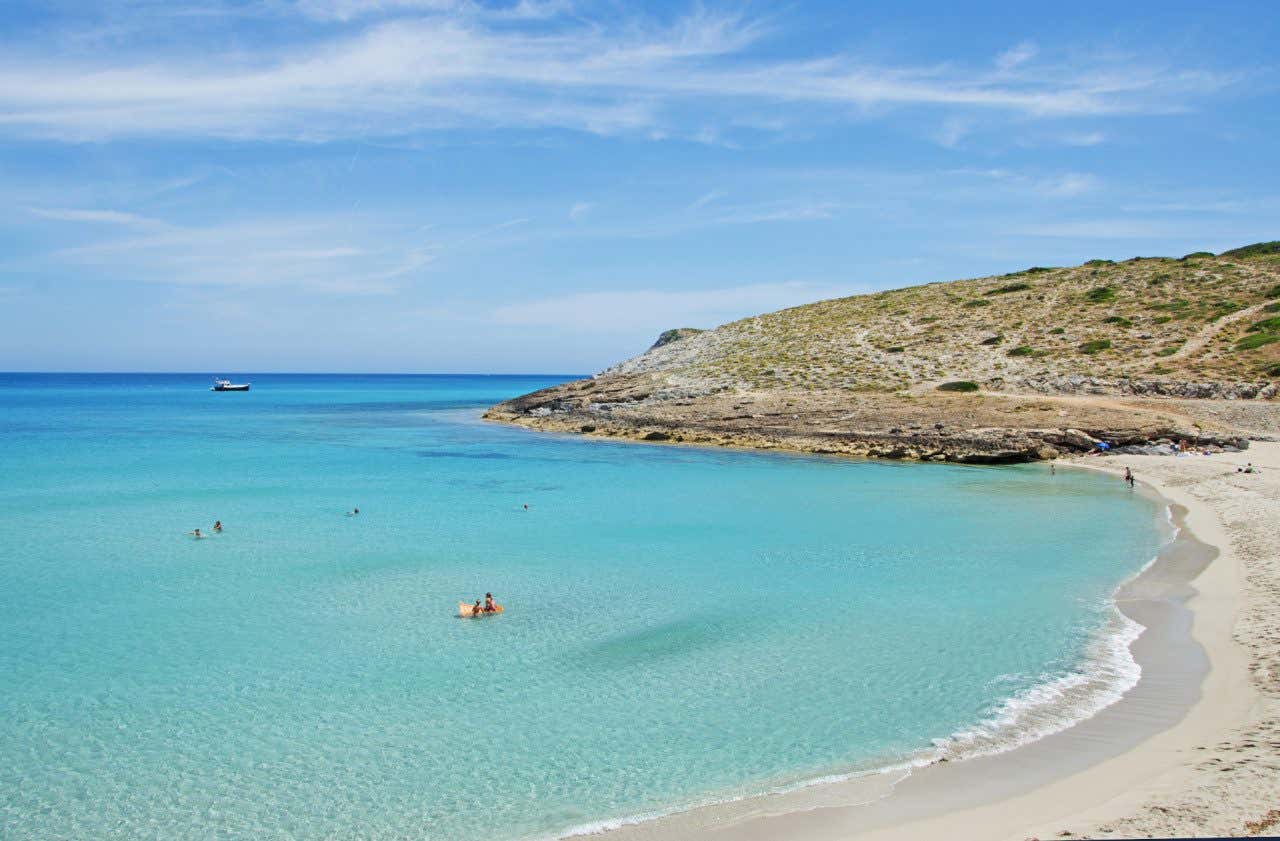 Panorâmica de Cala Torta, uma praia virgem em um ambiente natural com poucos visitantes na água e na areia