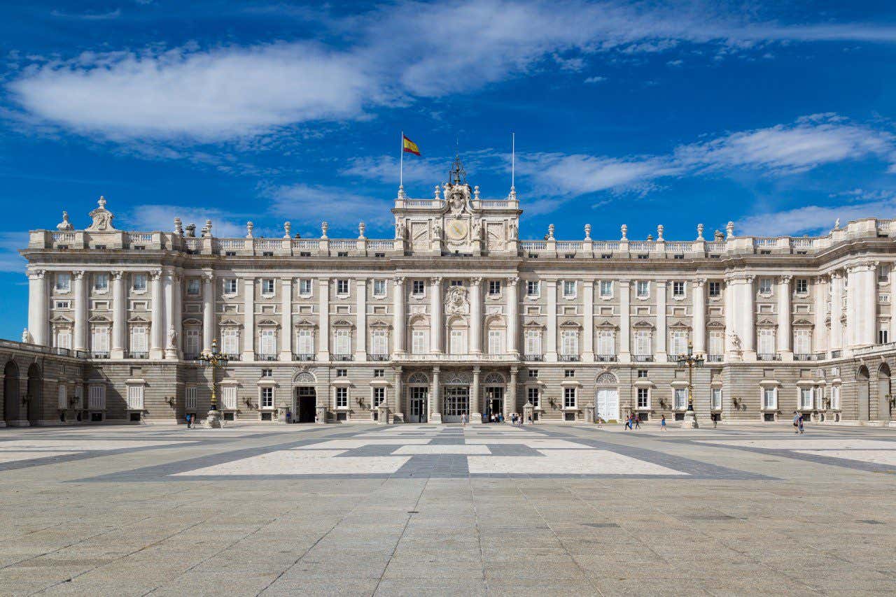 Fachada do Palácio Real de Madrid, ondeando a bandeira espanhola em um dia de sol