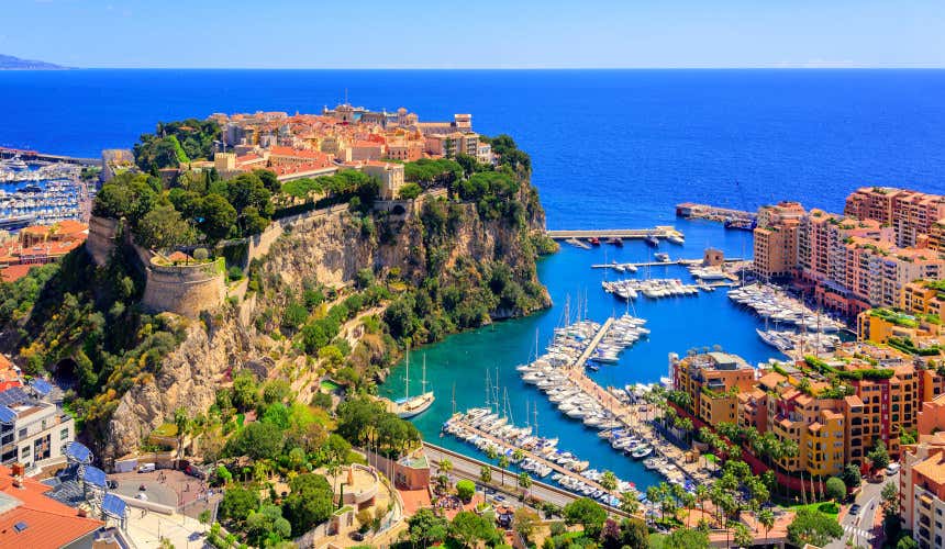 An aerial shot of Monaco´s bay, with boats moored in the port and orange buildings all along the waterline