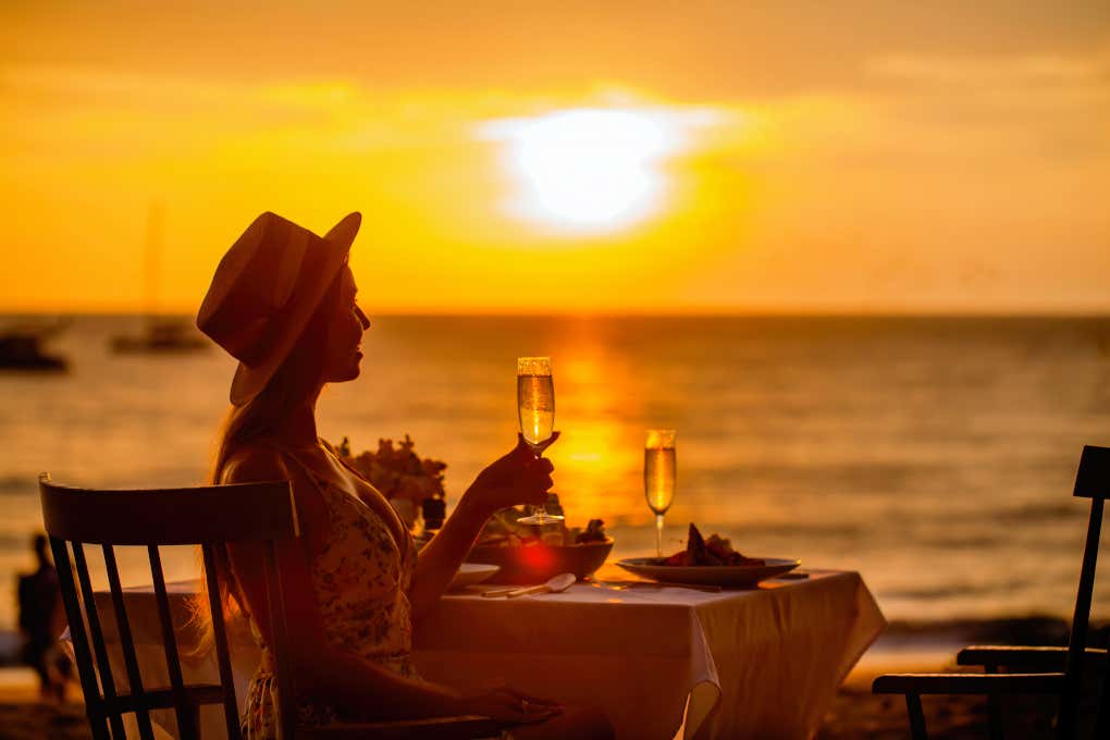 Una donna al tramonto mentre sorseggia champagne