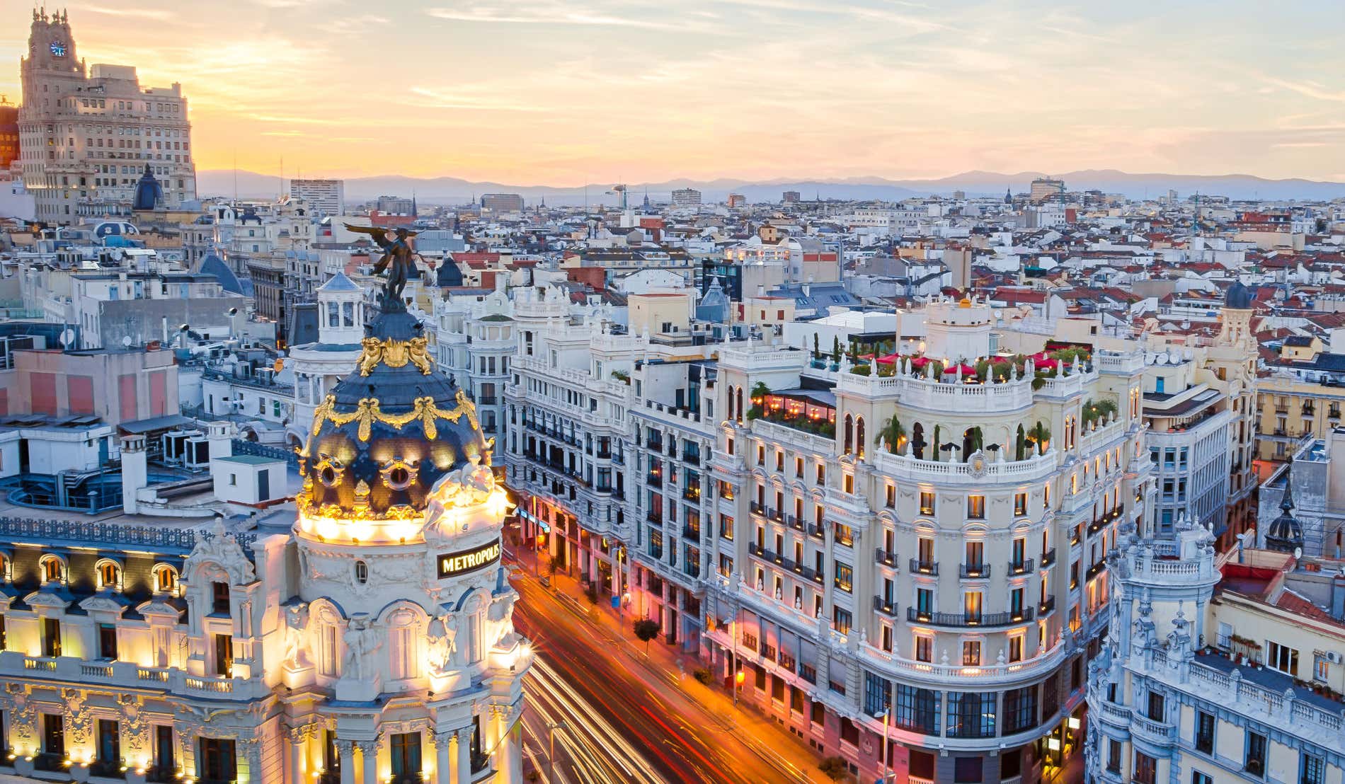 Vista desde las alturas de los edificios y rascacielos de la Gran Vía de Madrid iluminados al atardecer.