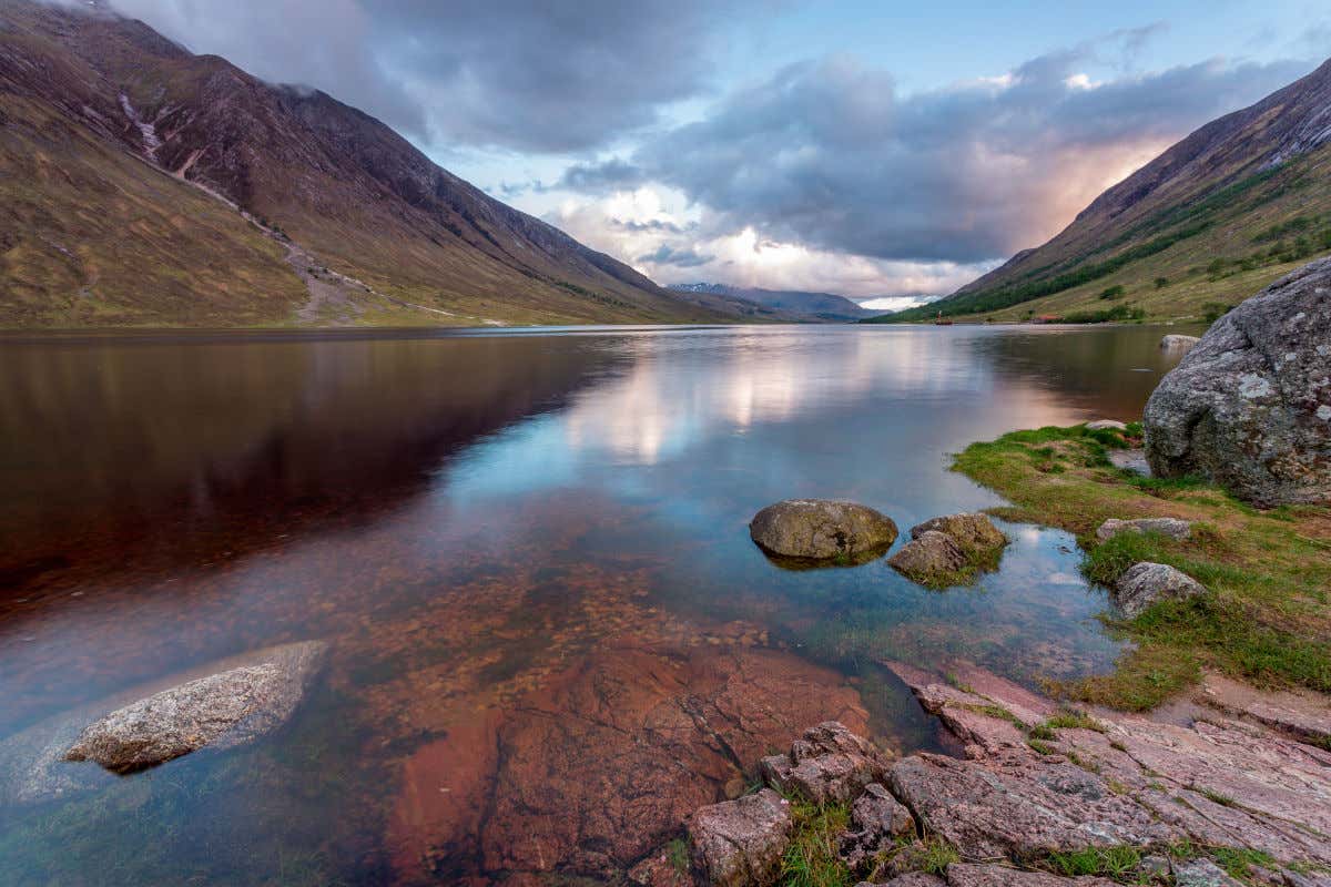 Panorâmica do lago Loch Etive, parte da rota do Harry Potter pela Escócia. com suas águas cristalinas que refletem as cores do céu e os tons esmeralda da vegetação que rodeiam a paisagem