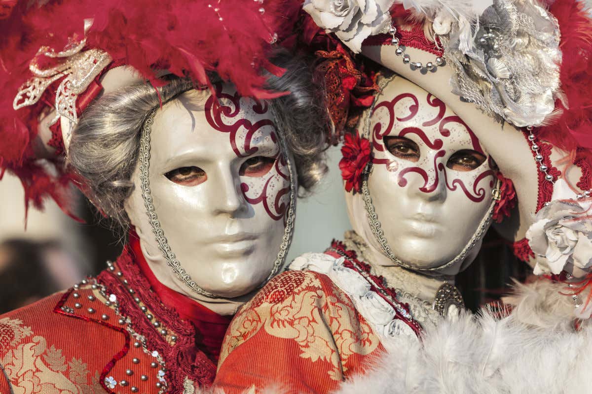 Una pareja ataviada con máscaras del carnaval veneciano.