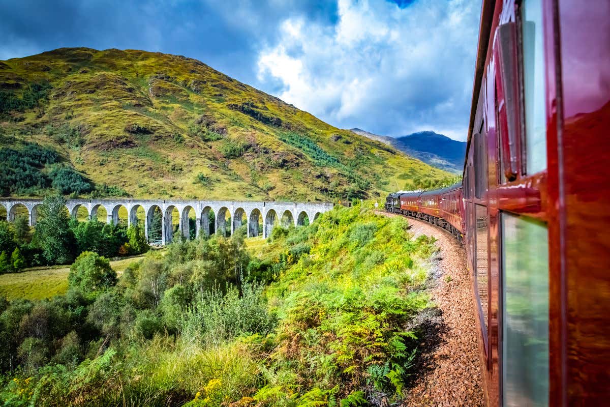 O trem Jacobite da Escócia atravessando o viaduto de Glenfinnan, um dos cenários mais famosos dos filmes de Harry Potter