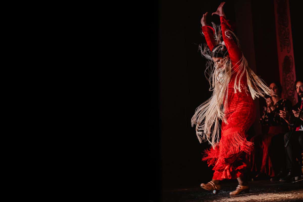 Une femme en mouvement avec une robe rouge dansant du flamenco au tablao flamenco La Pacheca