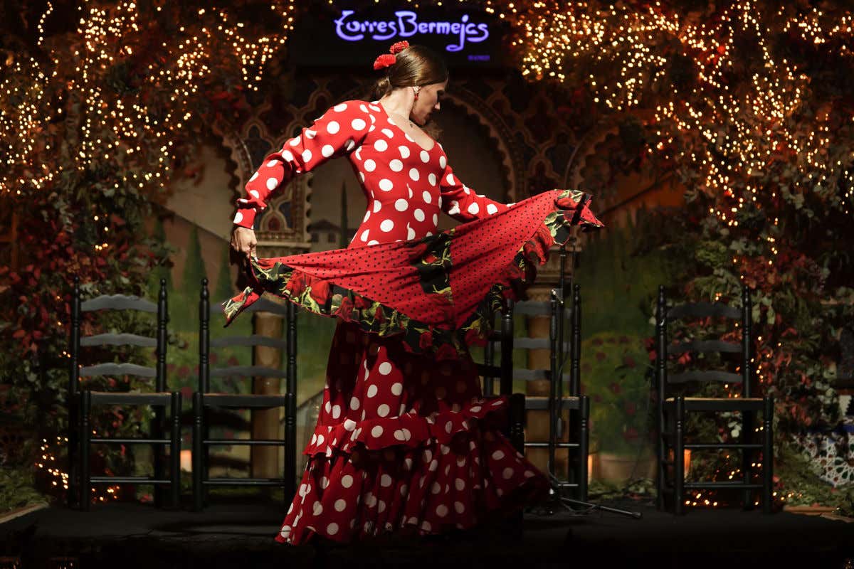 Une danseuse de flamenco avec une robe à pois dansant dans le tablao Torres Bermejas devant quatre chaises vides