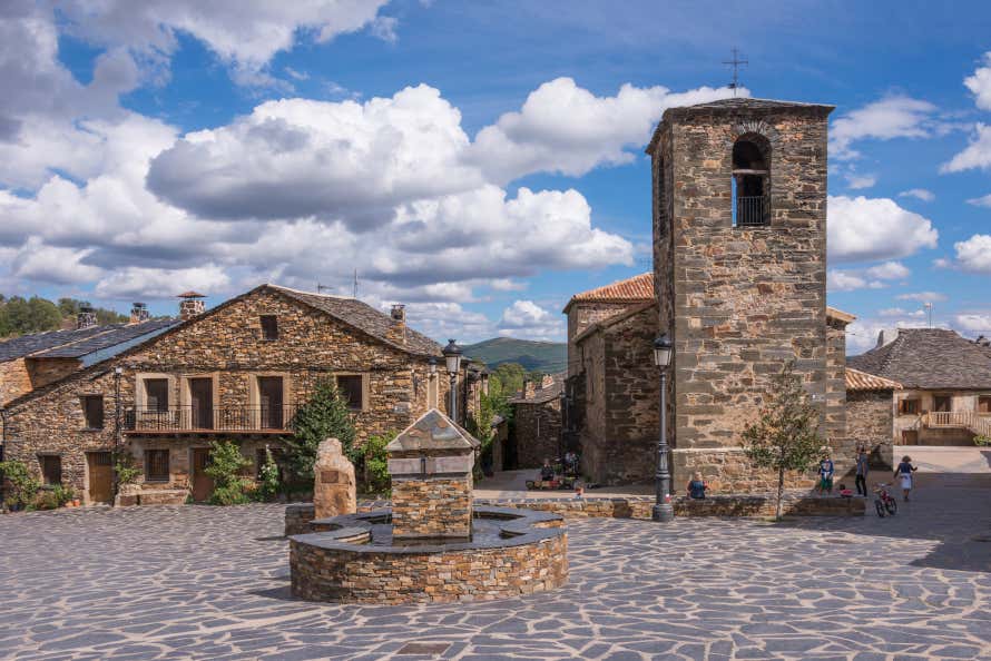 Plaza con edificios de pizarra y una fuente en Valverde de los Arroyos