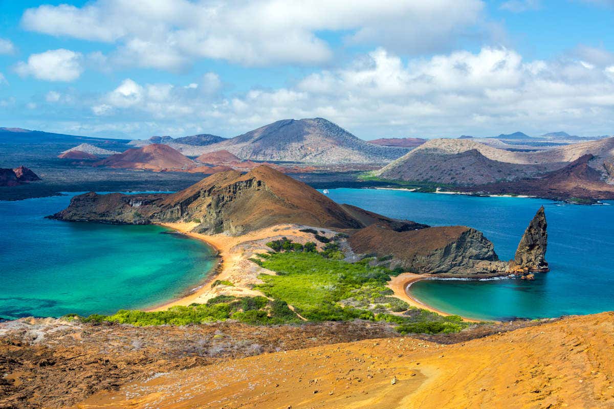 Views of Bartolomé volcano with turquoise waters and a blue sky with white fluffy clouds