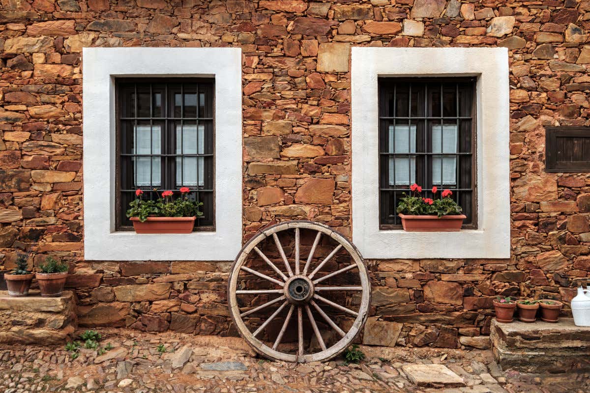 Dos ventanas y una rueda antigua en una casa de piedra en el pueblo de Castrillo de los Polvazares