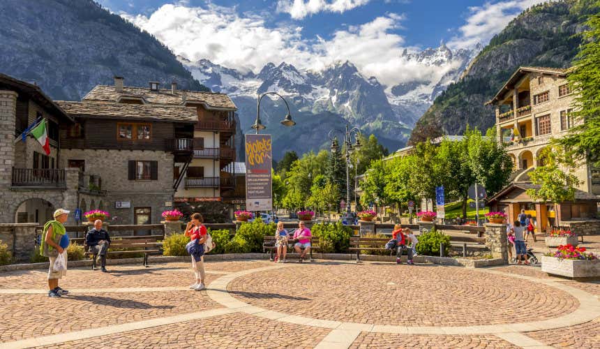 Plaza de Courmayeur em um dia de sol com alguns turistas e as montanhas nevadas ao fundo