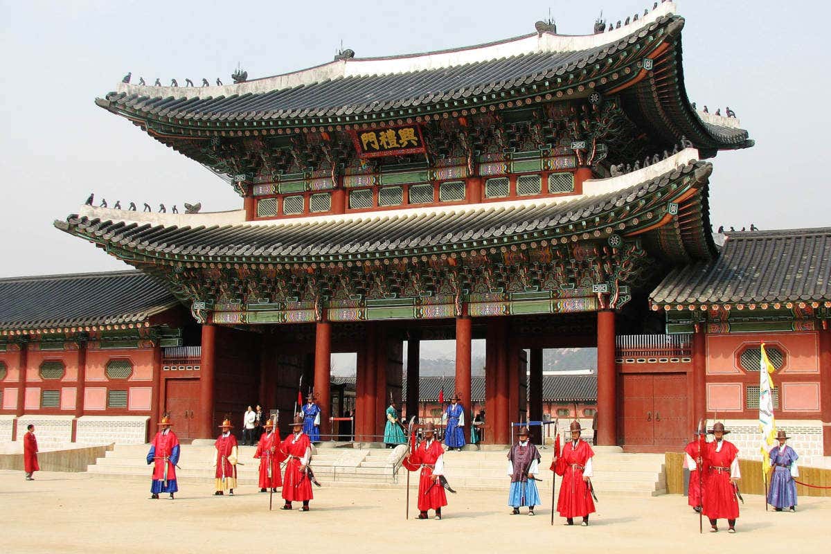 Hommes vêtus de costumes traditionnels devant une porte du Palais Gyeongbokgung