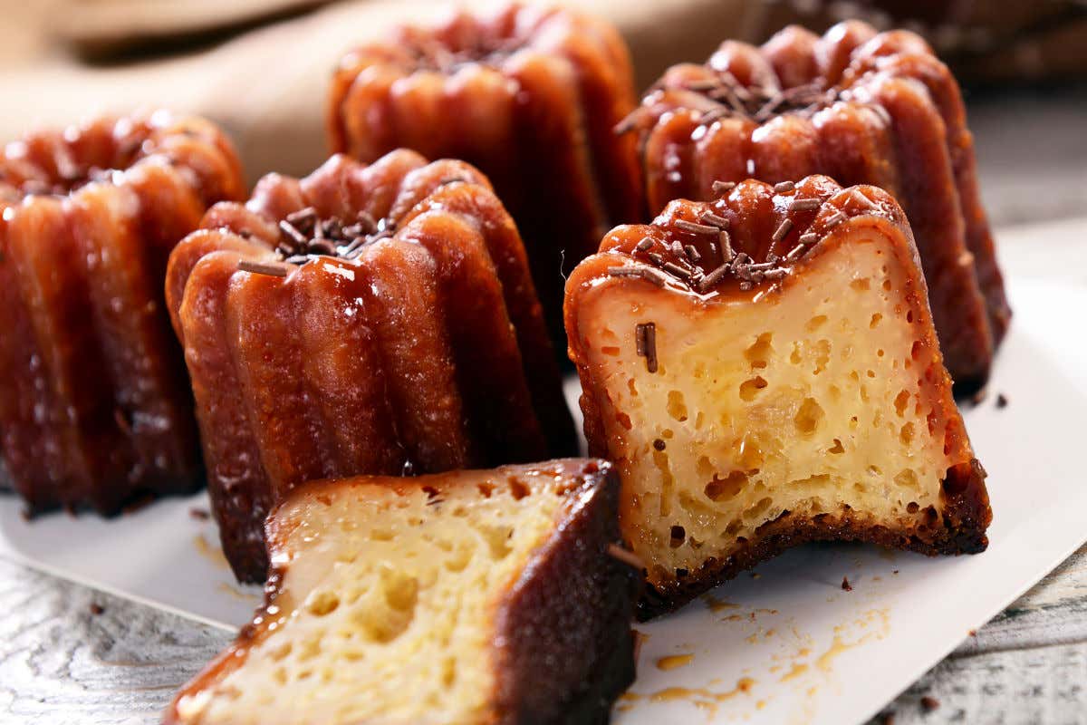 Diferentes cannelés em um prato, pequenos doces cor de caramelo com recheio esponjoso.