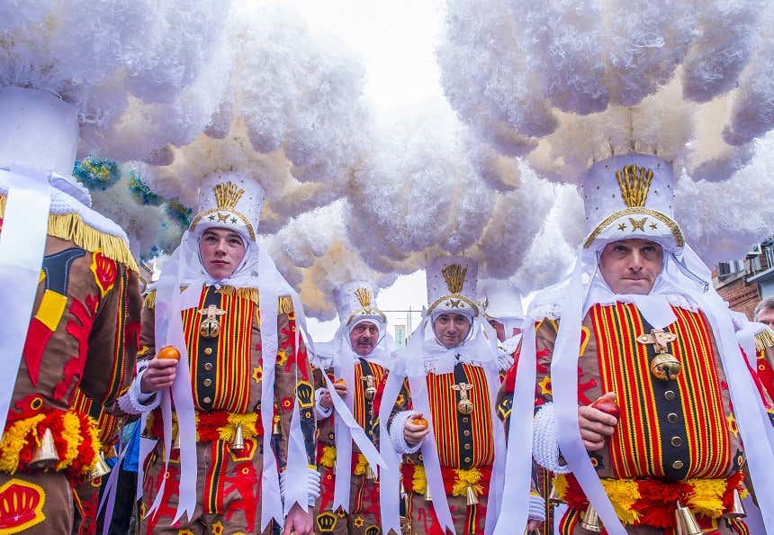 People wearing carnival costumes made up of colorful clothes and huge feathered hats