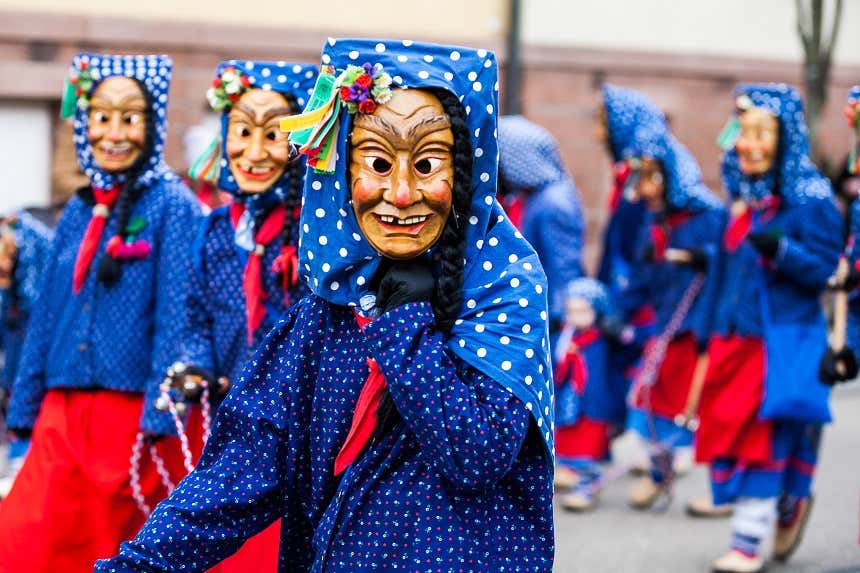 People in masks and scarves and blue clothes parading in the streets of Cologne