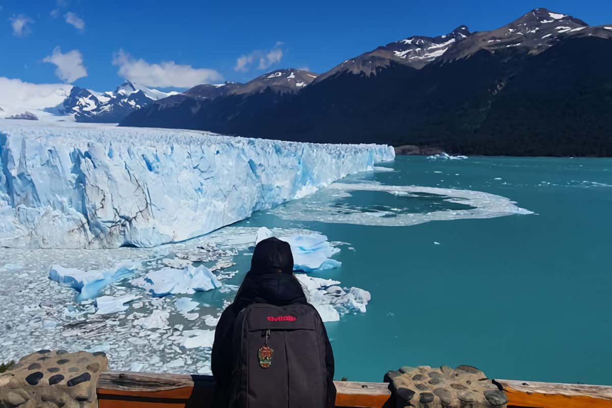 Romina Biggo de espaldas con una mochila con el logo de Civitatis admirando el glaciar Perito Moreno en El Calafate