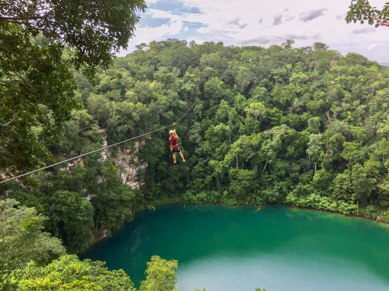 Woman ziplining over a cenote surrounded by lush foliage in the Mexican jungle