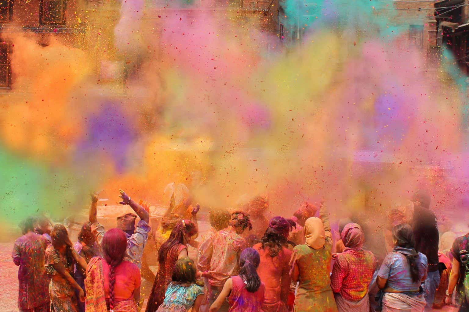 Donne indiane che lanciano polveri colorate per aria durante i festeggiamenti dell'Holi