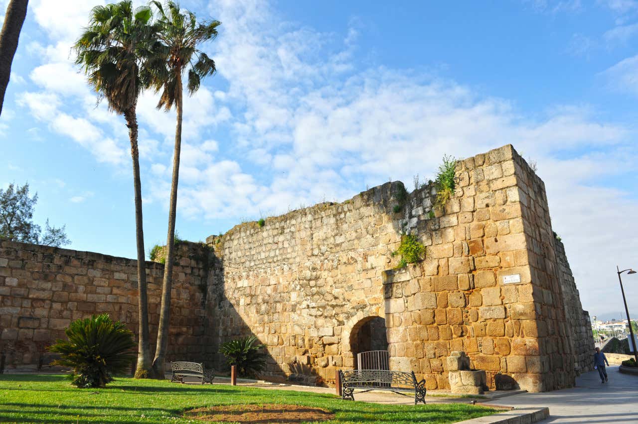 Entrada a la Alcazaba de Mérida, una construcción de piedra de aspecto sobrio tipo fortaleza junto a unas palmeras