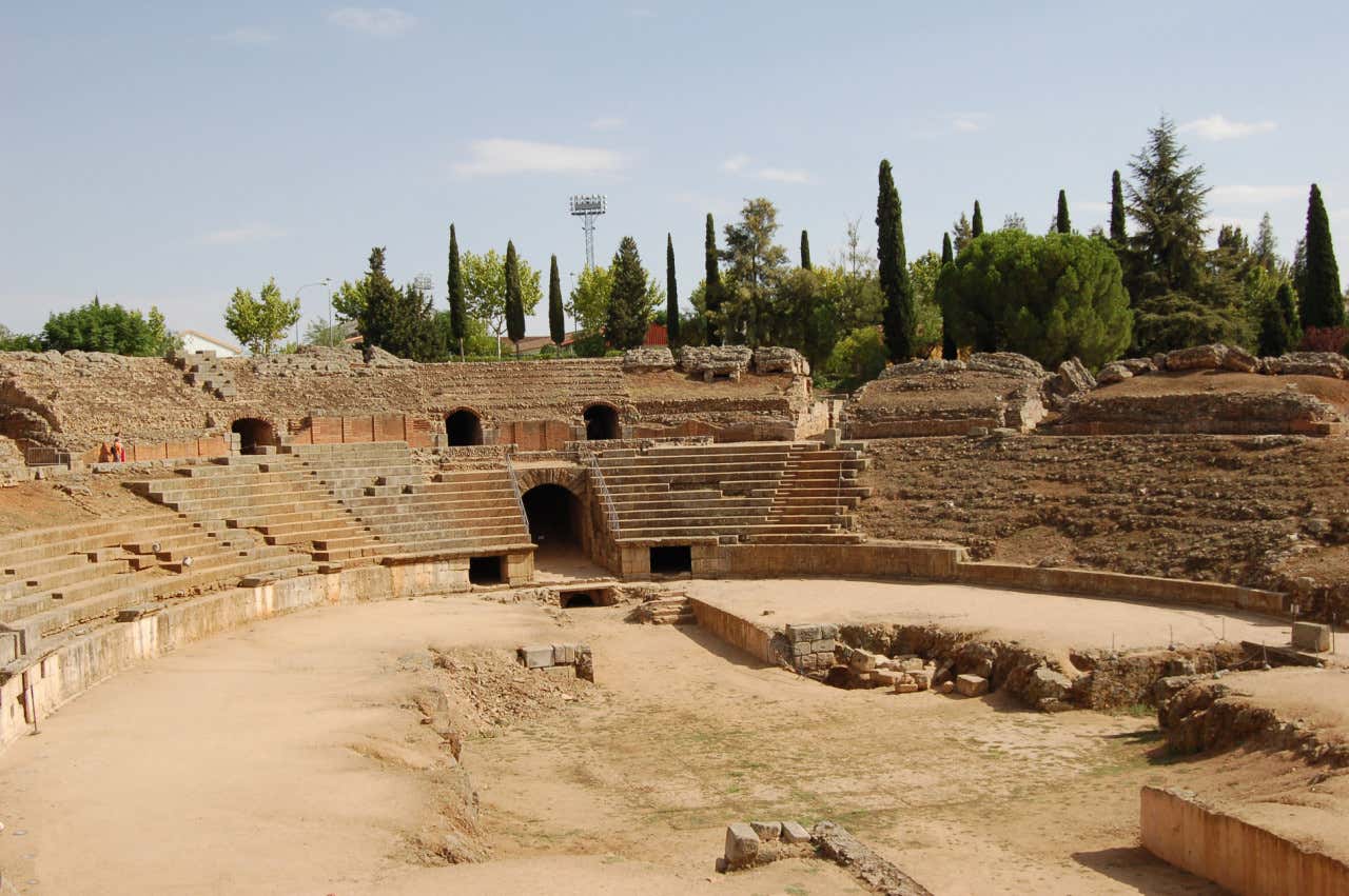 Arena del Anfiteatro romano de Mérida rodeado de gradas y varios cipreses