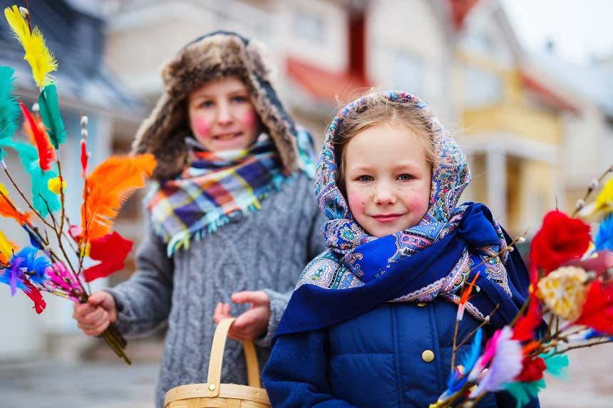 Duas crianças segurando ramos artificiais coloridos na Finlândia