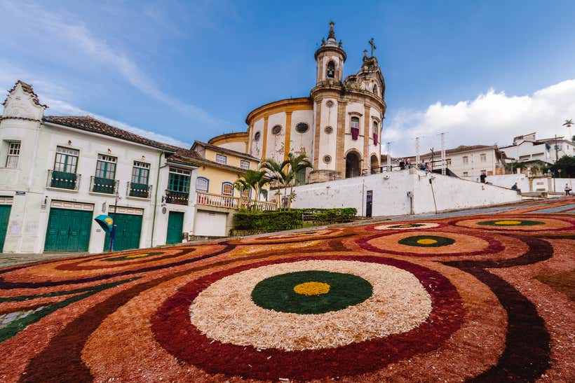 Tapete de flores e serragem decoram rua diante de igreja de Rio Preto
