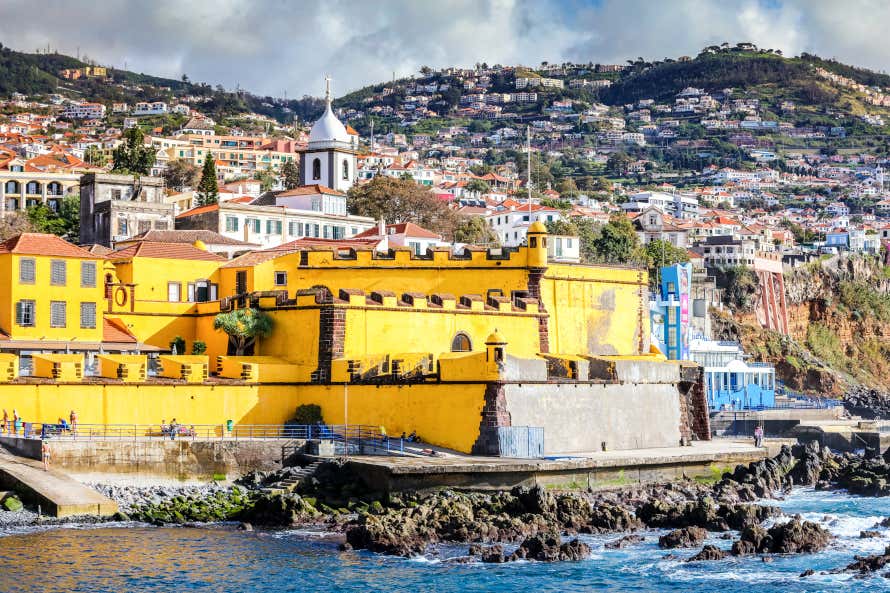 Fort of São Tiago, whose yellow colour contrasts with the rest of the houses in the city and the seashore