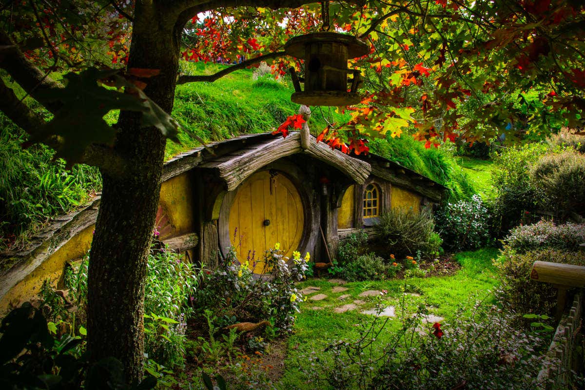 Pequena casa típica dos hobbits com uma porta redonda, instalada em um bosque da Nova Zelândia