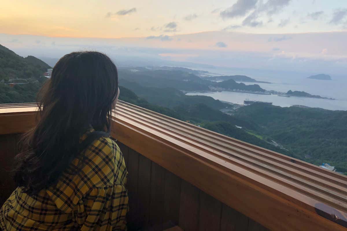 Karima El-Berjiji de espaldas a la cámara contemplando un atardecer en el norte de Taiwán