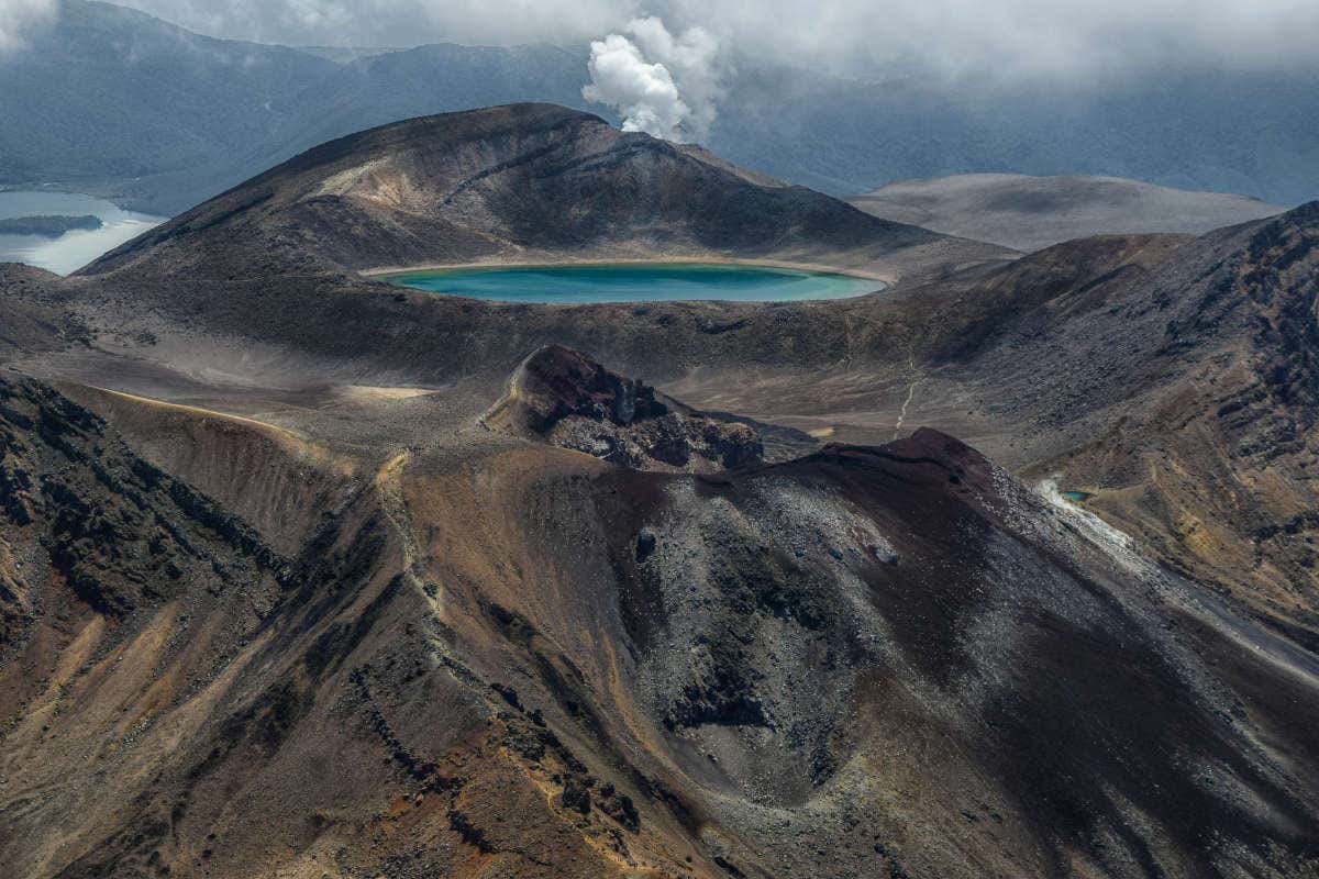 Monte Ngauruhoe, em tons escuros, com uma lagoa no centro