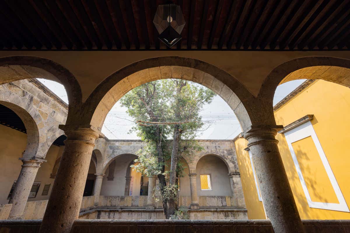 Patio con arcadas de piedra y un árbol en el centro del Museo Regional de Guadalajara, en México