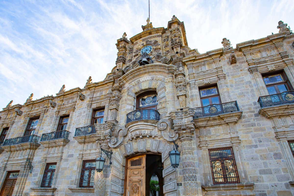 Fachada principal del Palacio de Gobierno del Estado de Jalisco con balcones de forja y una campana junto al reloj central