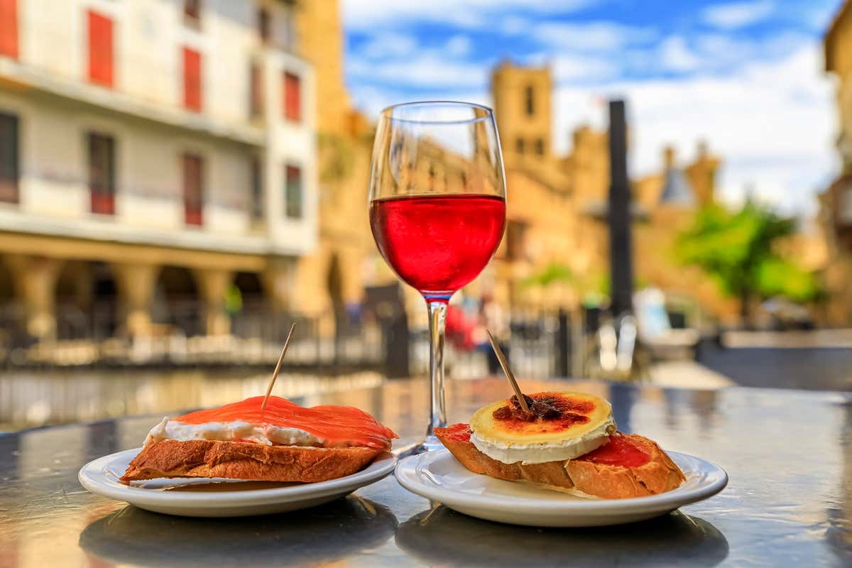 Gros plan sur un verre de vin rouge et deux pintxos sur une table en terrasse