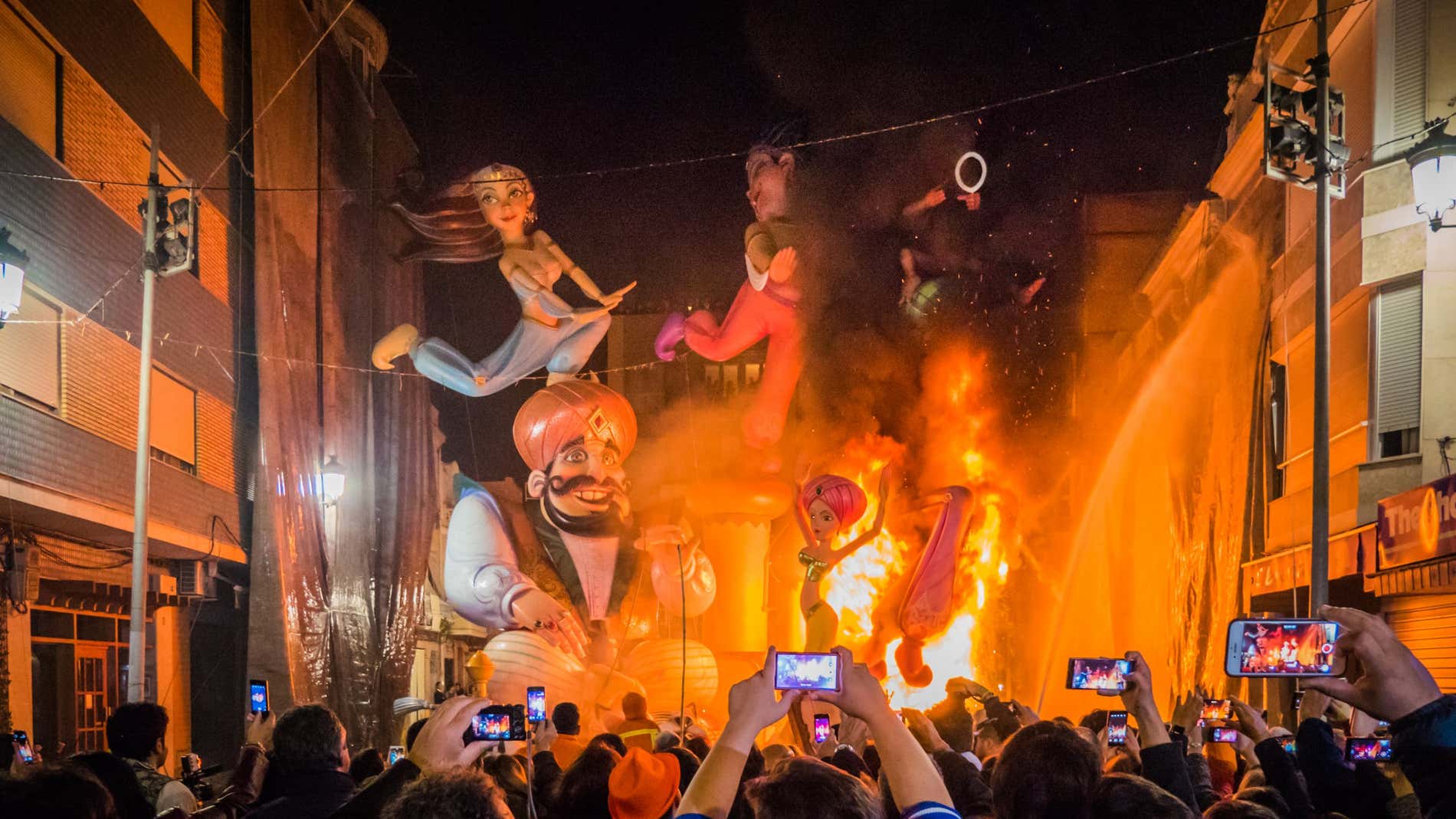 People take photos of large colourful effigies set on fire at night