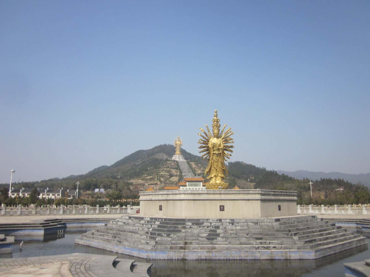 Une statue dorée représentant une divinité avec plusieurs bras sur un promontoire