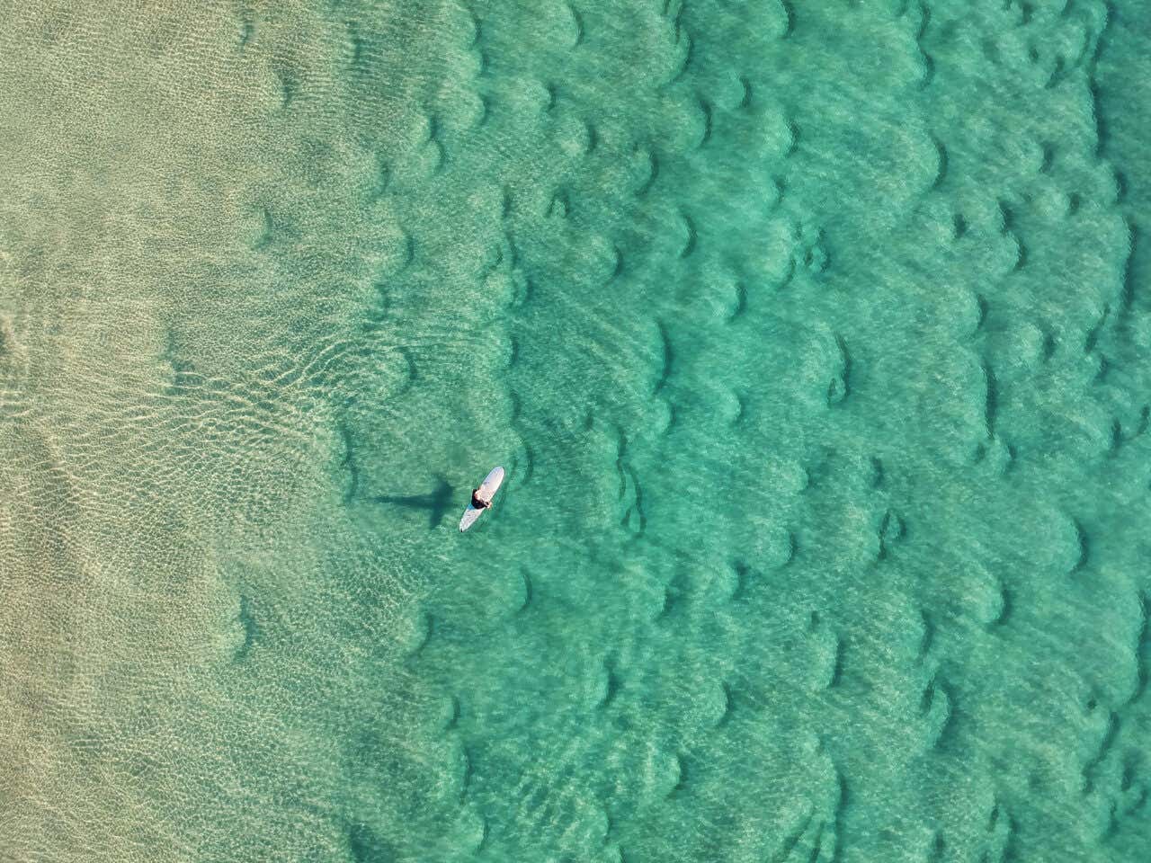 Vue aérienne sur un surfeur dans une mer cristalline