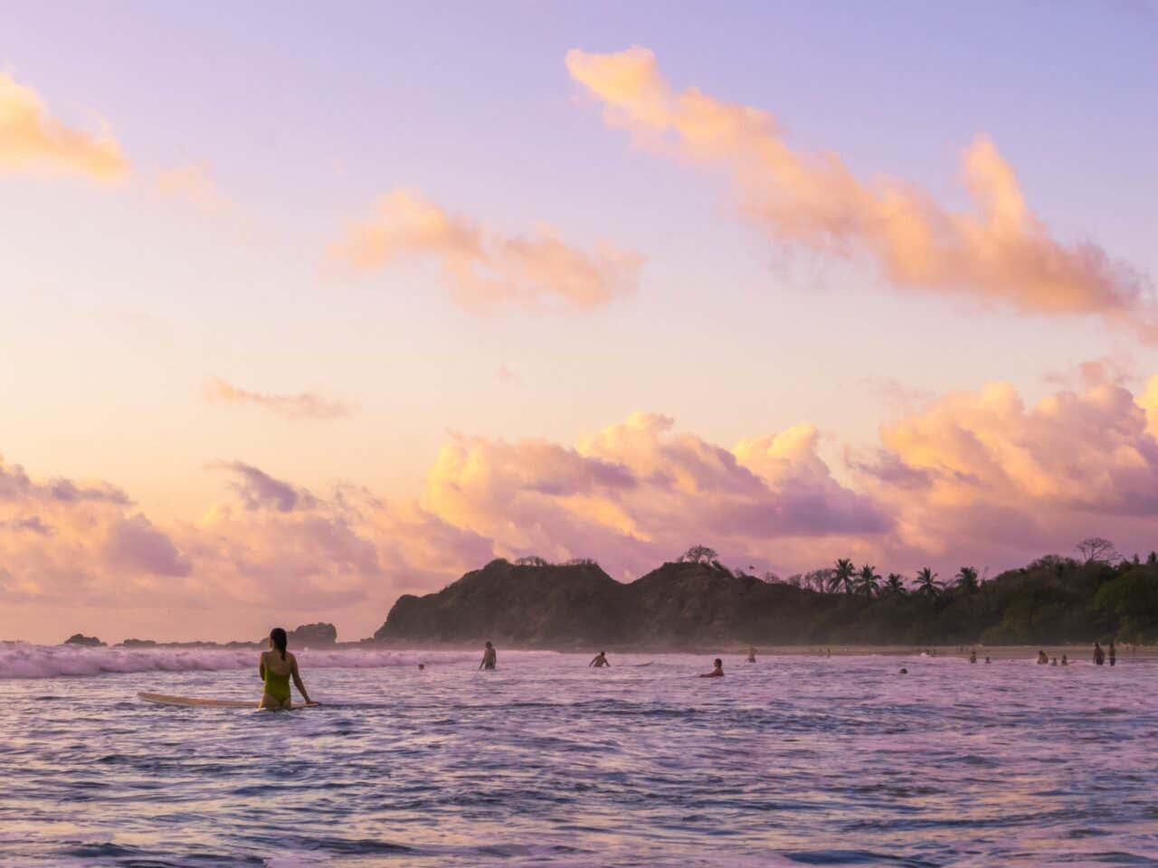 Surfeurs dans la mer au coucher de soleil au Costa Rica avec de la végétation en arrière plan