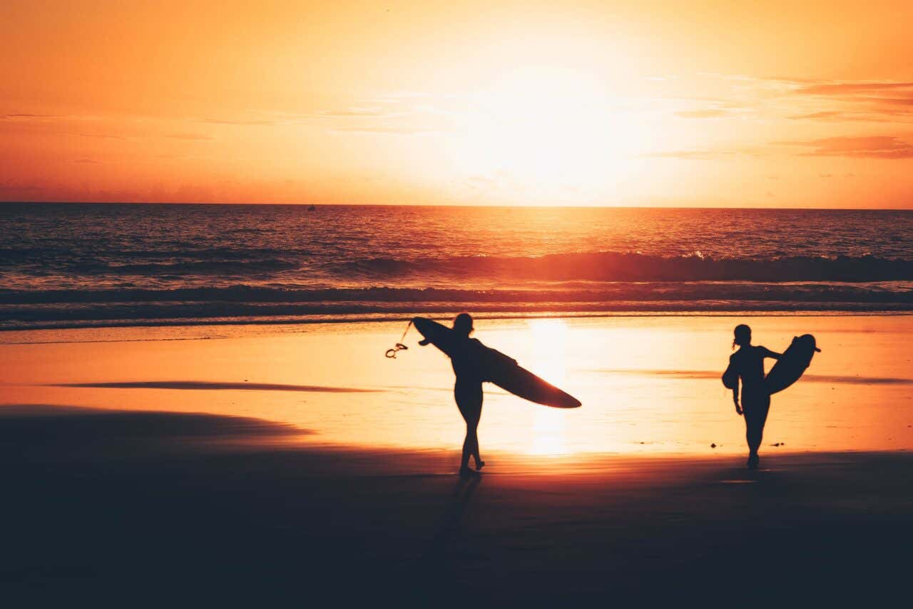 Deux surfeurs sur une plage marocaine au coucher de soleil