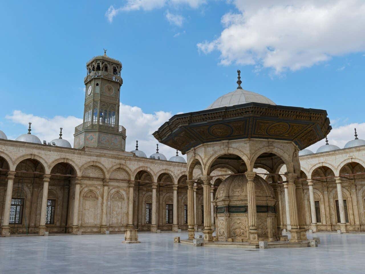 Cour de la mosquée Muhammad Ali, avec une colonnade, une fontaine et une horloge