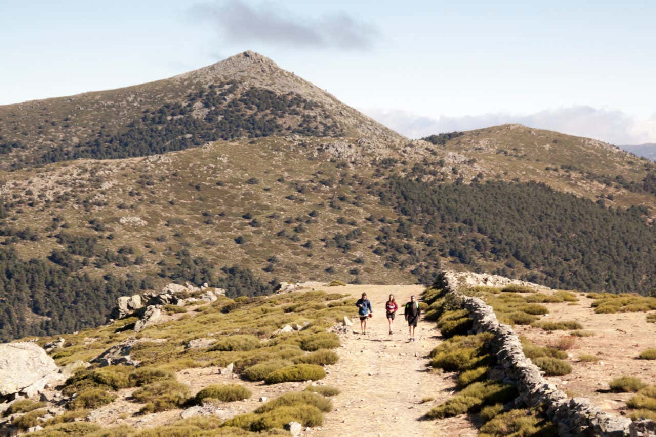 Trois personnes au loin sur un sentier dans la Sierra de Guadarrama, collines en arrière-plan