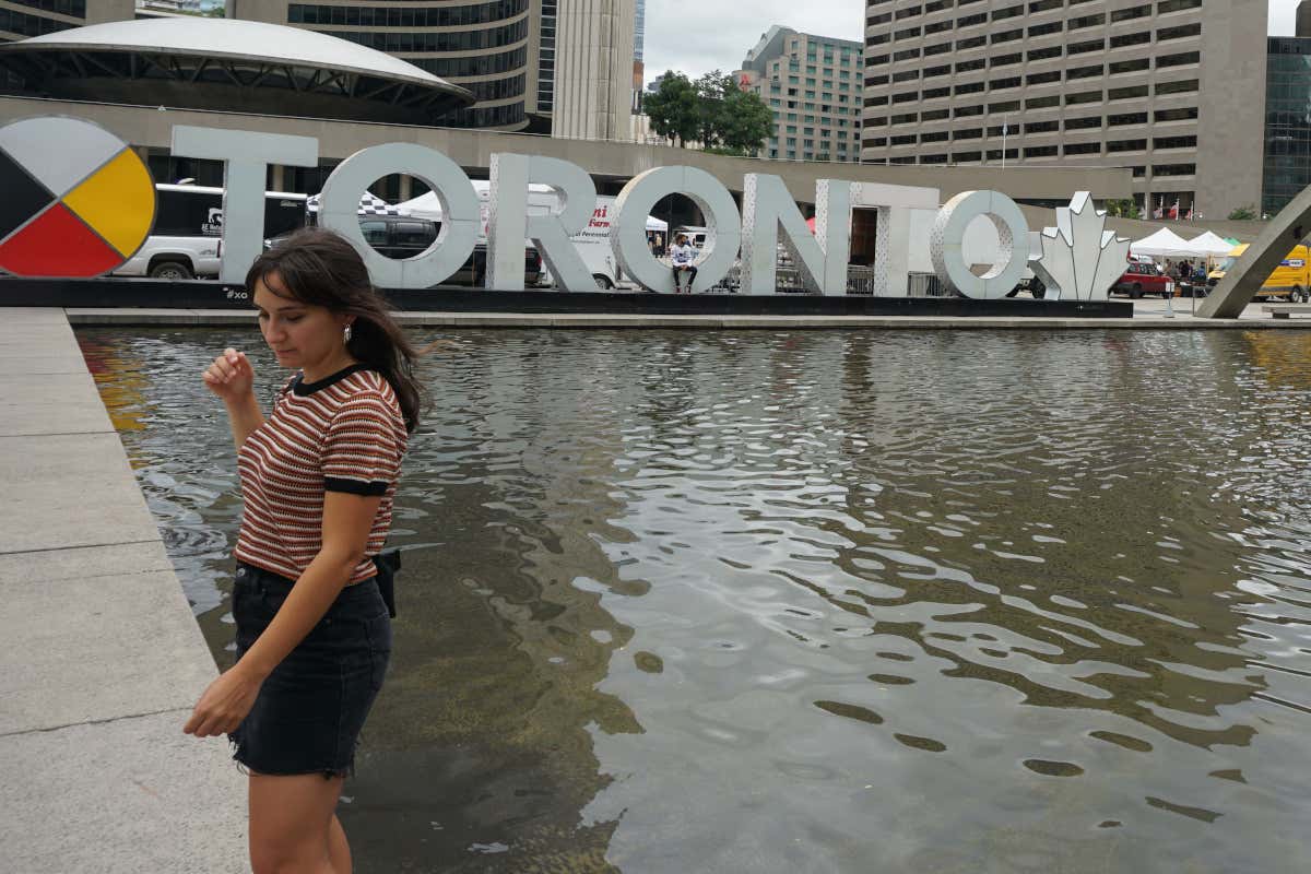 Una mujer frente al cartel con las letras de Toronto, en la ciudad canadiense