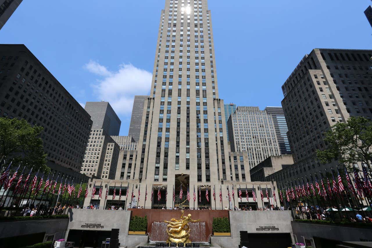 An image of the Rockefeller Center taken from below, with a clear blue sky above