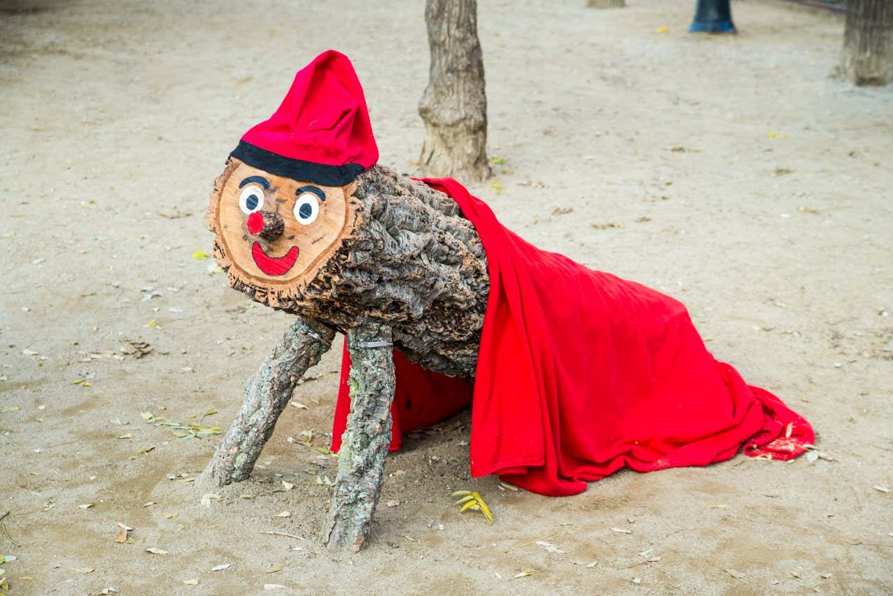 Un tronco con una cara feliz, un sombrero y una manta, llamado Tió de Nadal en Cataluña.