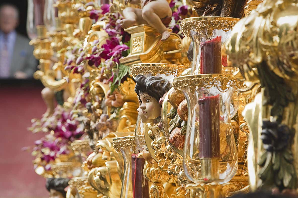 Un altar dorado con diferentes velas y pequeñas esculturas de la Semana Santa de Sevilla