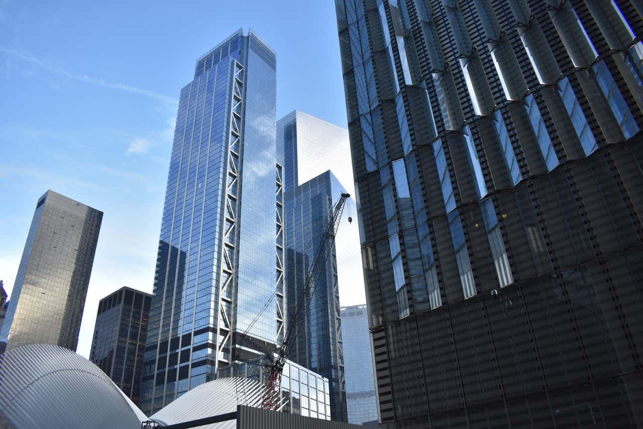 Three World Trade Center seen from street level with a mostly clear blue sky in the background