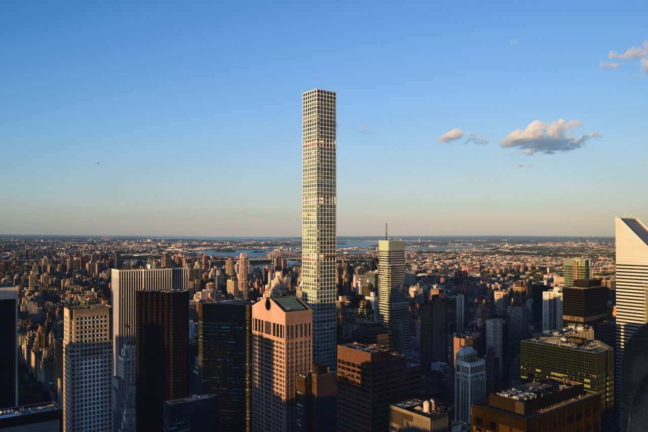 432 Park Avenue as seen from afar against a blue sky with a few clouds in the sky